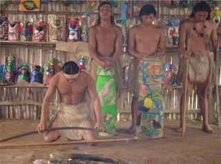 Maleku Shaman conducting sacred fire ceremony called, Nature, Man and God, in traditional palenque hut. Painted balsa Maleku Tazi drums are used in the ceremony.